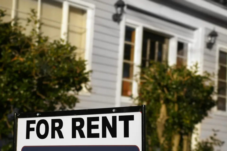 For rent sign with blurry house in background